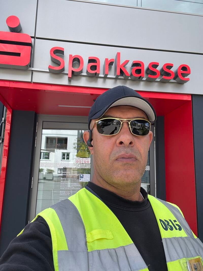 Mitarbeiter in Einsatzkleidung vor dem Eingang einer Bankfiliale