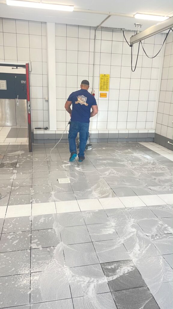 F.S.-Mitarbeiter von hinten bei der Bodenreinigung mit einer Einscheibenmaschine